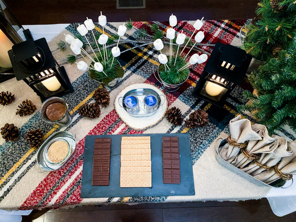 How to make s'mores at home is easy with all of these s'more ingredients, it's also a great way to make s'mores without a fire, this plaid table with galvanized pails and black lanterns is the perfect backdrop for the s'more bar station. It's a great way to make indoor s'mores.