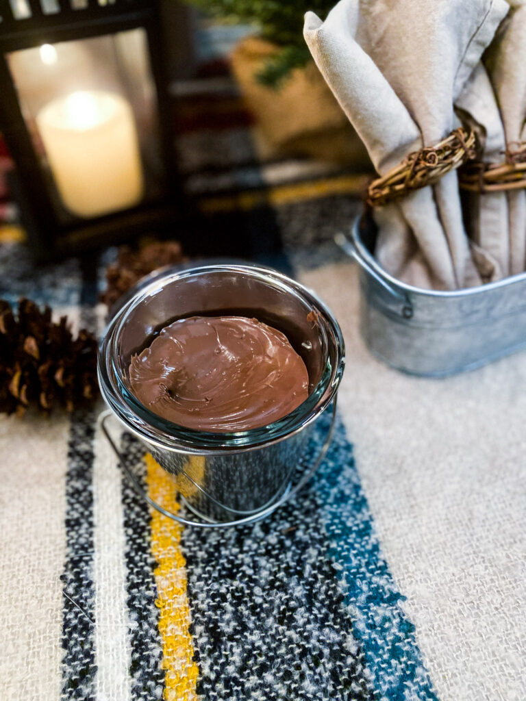 This is a great s'mores dip recipe that is also boozy. The chocolate dip is served in a galvanized bucket with a pinecone as an accent on the table.