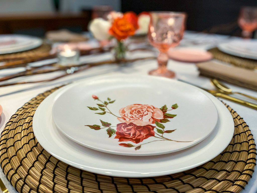 Coral roses in a small bud vase, surrounded by wooden twigs is the perfect complement to the vintage colored glassware on the tabletop.