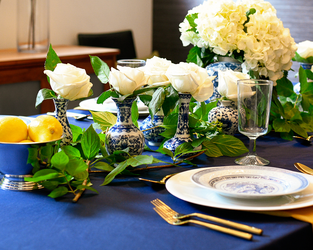 Blue and white tablescape idea with chinoiserie, hydrangeas, white roses, and gold utensils.