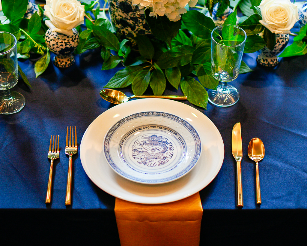 Blue and white table setting idea with gold flatware, metallic gold napkins and chinoiserie vases.