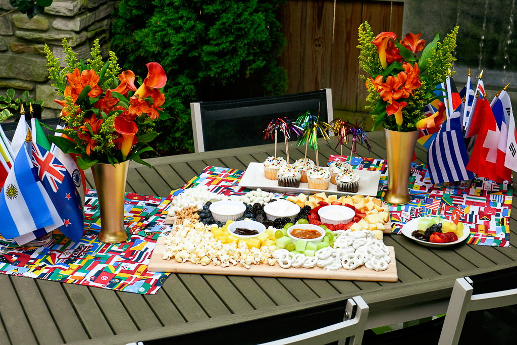 An Olympic theme tabletop with a charcuterie board, DIY olympic torch centerpieces and fireworks cupcakes. Olympic party ideas.