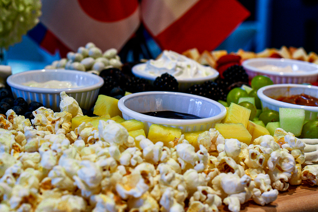 A clever charcuterie board with Olympic rings made from fruit, as well as fruit dips. Olympic party ideas.