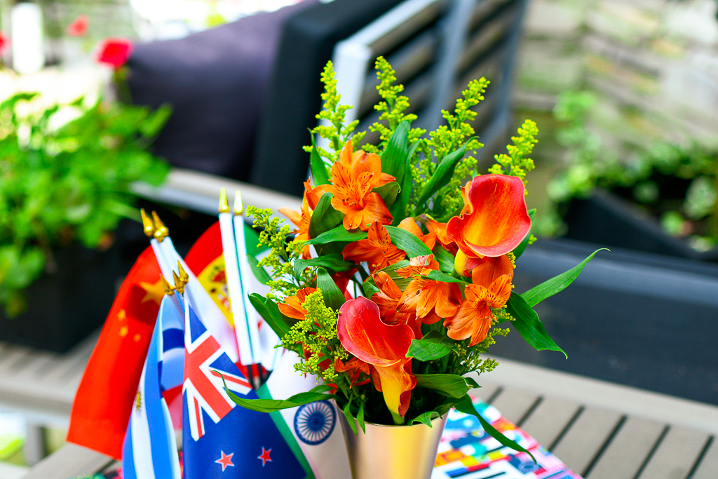 A gold vase with orange flowers that looks like an Olympic torch and an Olympic flame.