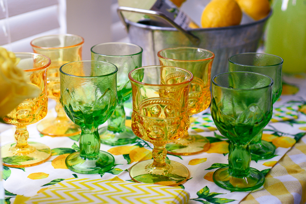 Green vintage glassware, yellow vintage glassware, lemon table runner, yellow and white checked tablecloth, galvanized pail with lemons, all great summer party themes and lemon party theme ideas. It's also cute lemonade stand ideas with lemonade cocktail recipes, as party of a lemonade party idea.