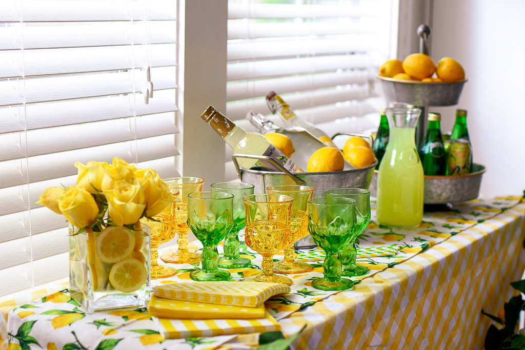 what is limoncello, the best limoncello recipe, limoncello cocktail, limoncello recipes, limoncello martini, summer party ideas, galvanized tub with lemons and lemon flavored liqueur, lemonade, galvanized tiered tray with lemons, lemon table runner, vintage yellow and green glasses, lemonade cocktails, best alcohol to mix with lemonade, lemonade cocktail with vodka, lemonade cocktails, summer party decoration, lemon theme party ideas, 