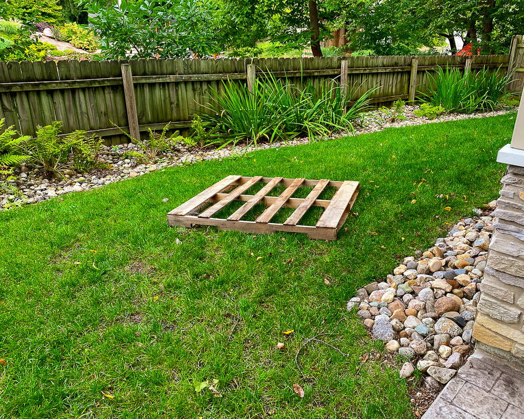 A pallet picnic table sits on green grass. Romantic picnic ideas.